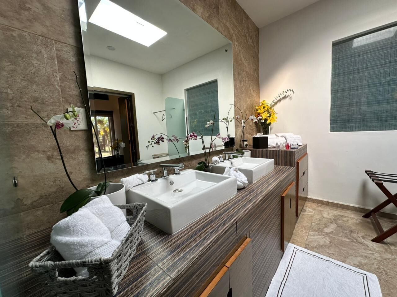 Un baño moderno con dos lavabos, un espejo grande y un perchero para toallas.