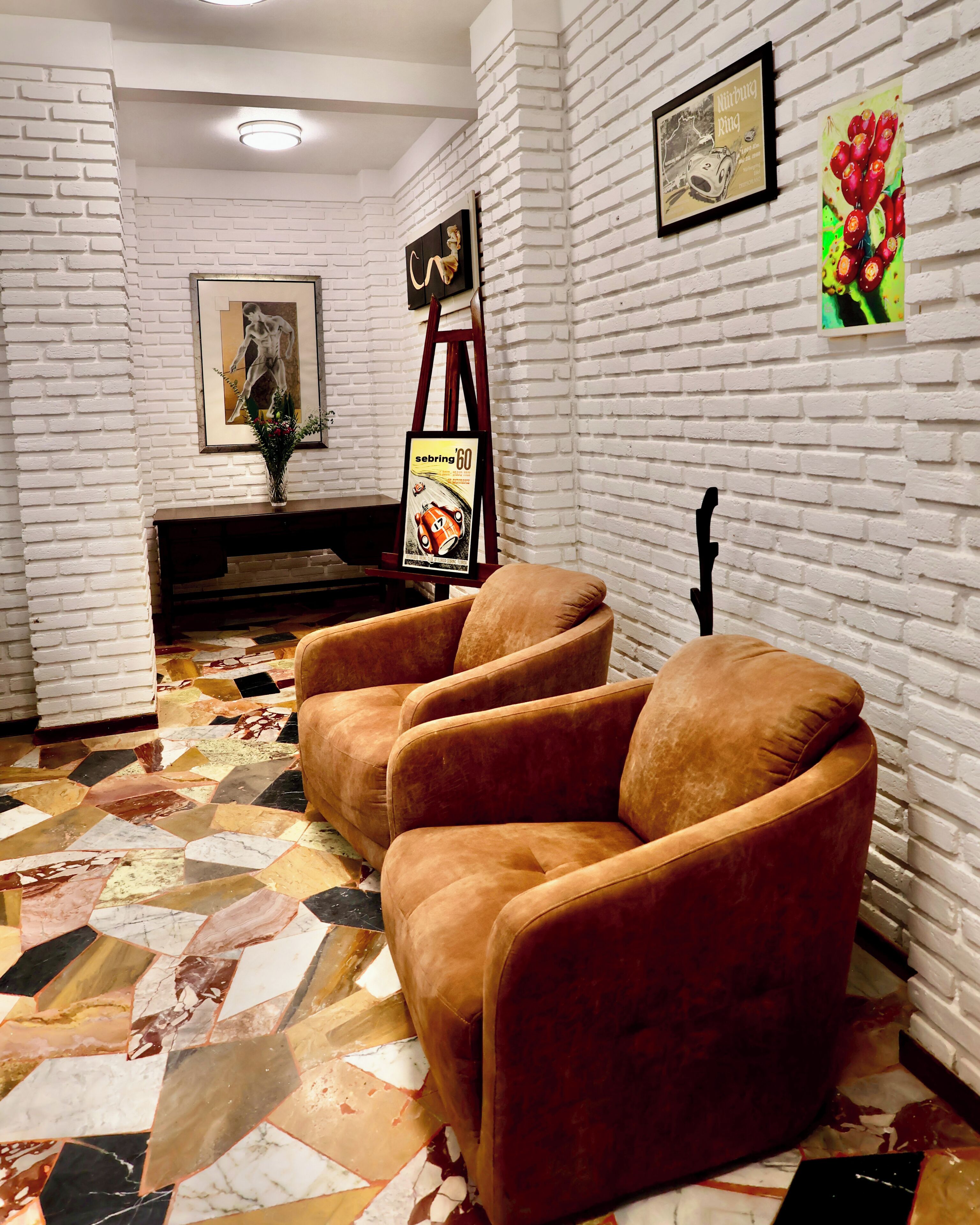 A room with a white brick wall, a framed picture, a poster, and a patterned floor.