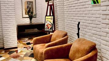 A room with a white brick wall, a framed picture, a poster, and a patterned floor.