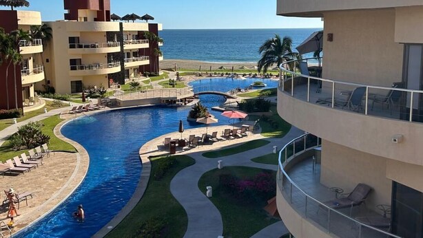 Un resort con una piscina grande, varios balcones y vistas al océano.