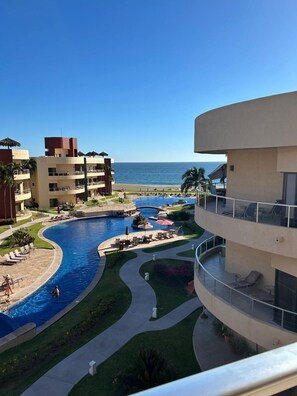 Un resort con una piscina grande, varios balcones y vistas al océano.