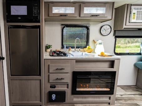 Fridge, microwave, stovetop, cookware/dishes/utensils. Shaanti Living • Cozy Private Camper 1
