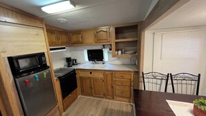 Una cocina compacta con armarios de madera, microondas integrado, estufa y lavamanos.