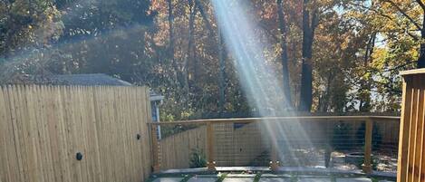A backyard with a wooden deck, a fire pit, and a wooden fence.