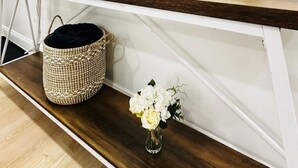 A wooden console table with a round mirror, a clock, a potted plant, a woven basket, and a vase with flowers. - Feels Like Home - BBQ, Yard, Fire Pit (Fitchburg)