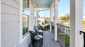 A covered porch with two chairs, a railing, and a view of the street. - 4br home near The Nations with easy access to local attractions (Nashville)