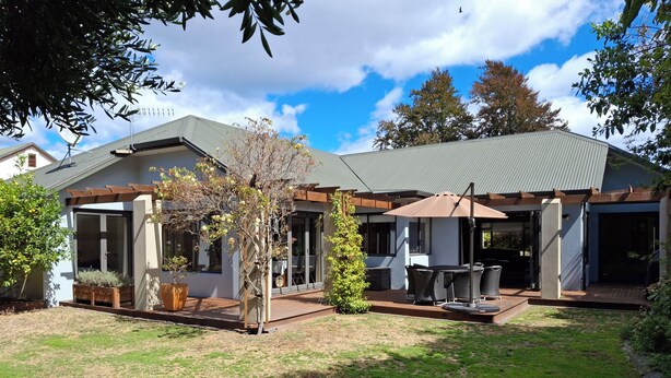 A modern house with a patio area featuring outdoor furniture and a pergola.