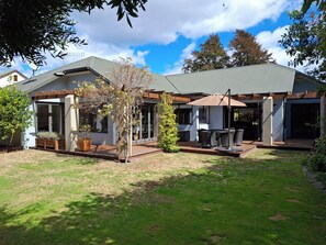 Een modern huis met een terras, straal het buitenmeubilair en een pergola.