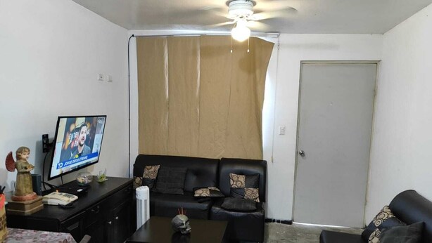 A living room with a sofa, a coffee table, a television, and a ceiling fan. - department (García)