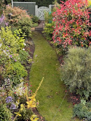 Stroll through the serene garden, surrounded by vibrant flowers and lush greenery, leading to an entrance.