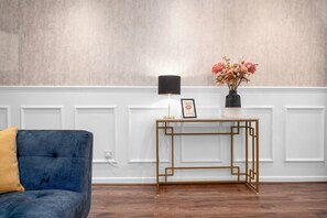 Relax on the sofa, surrounded by a stylish side table and a beautiful vase with flowers.