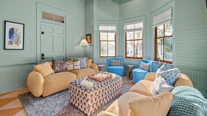 A cozy living room with a beige sofa, a blue sofa, and a patterned ottoman. There is a lamp, a small table, and a framed picture on the wall. - Midnight Moon Retreat (Beaufort)