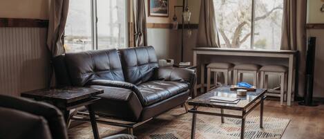 A living room with a leather sofa, a coffee table, and a dining table.