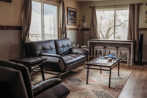 Una sala de estar con un sofá de cuero, una mesa de centro y una mesa de comedor.