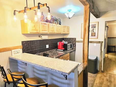 A kitchen with wooden cabinets, a granite countertop, a red coffee maker, and a microwave.