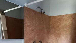 Ein Badezimmer mit einem Standwaschbecken, einer Dusche und einem Spiegel.