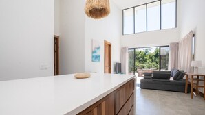A modern kitchen with a large island, wooden cabinets, and a hanging light fixture.
