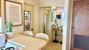 A modern kitchen with a dining area, featuring a large island, chairs, and a potted plant. - Hilo Studio Retreat with Gorgeous Park View, AC, WiFi, Pool (Hilo)
