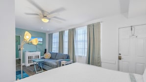 A bedroom with a bed, a desk, a chair, a ceiling fan, and a door. - Coastal Getaway Retreat–Steps to the Beach! Studio/1BA. Sleeps 2. In 4-Plex.Pool (Bradenton Beach)
