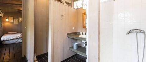 A wooden interior with a bed, a sink, and a shower.
