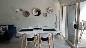 A dining area with a white table and chairs, a blue sofa, and decorative wall art.