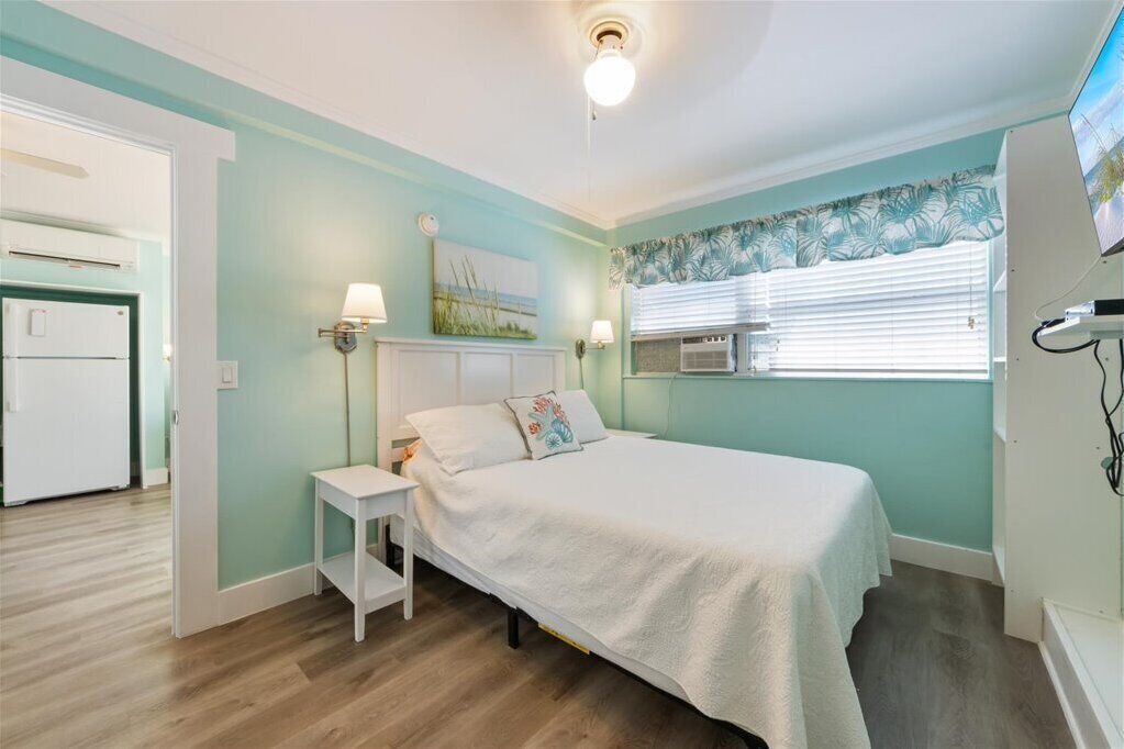 Ein Schlafzimmer mit Bett, Nachttisch, Lampe und einem Gemälde an der Wand.