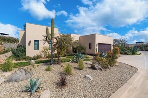 A modern two-story house with a desert garden, including cacti and agave plants.