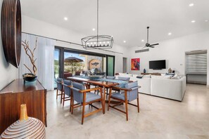 A modern living room with a dining area, a TV, and a ceiling fan.