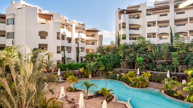 A modern hotel with multiple white buildings, a swimming pool, and lush greenery. - Jardines - Adama 1.3 POOL VIEW (Arona)