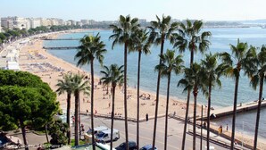 Ein Strand mit Palmen, einer Promenade und einer Stadtkulisse im Hintergrund.