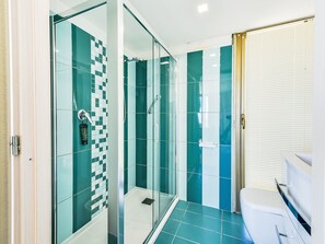 A modern bathroom with a glass-enclosed shower, a toilet, and a sink.