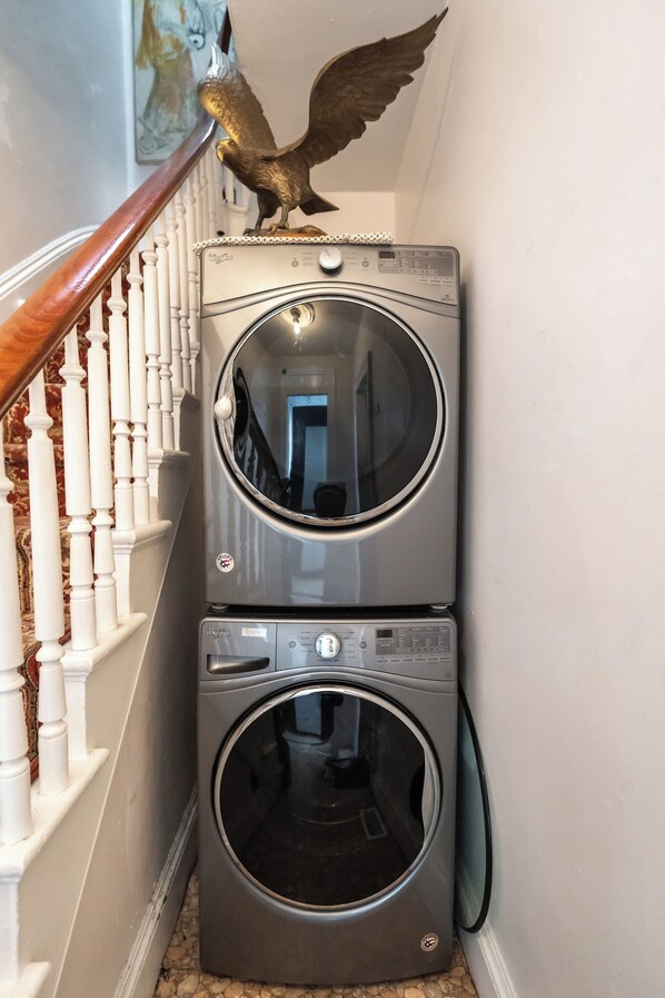 A laundry area with two stacked front-loading washing machines and a wooden handrail. - Chic & Comfortable 1 bed apt with Parking. Walking distance JSQ path. Sleeps 4.  (Jersey City)
