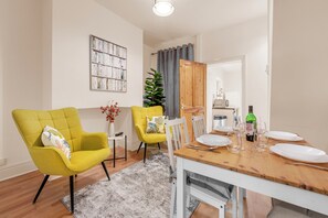 Enjoy meals in this stylish dining area with a dining table for four, comfortable armchairs, and a beautiful potted plant.