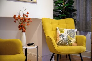 Relax in this inviting living room with a comfortable armchair, a vase with fresh flowers, and a lush green plant.