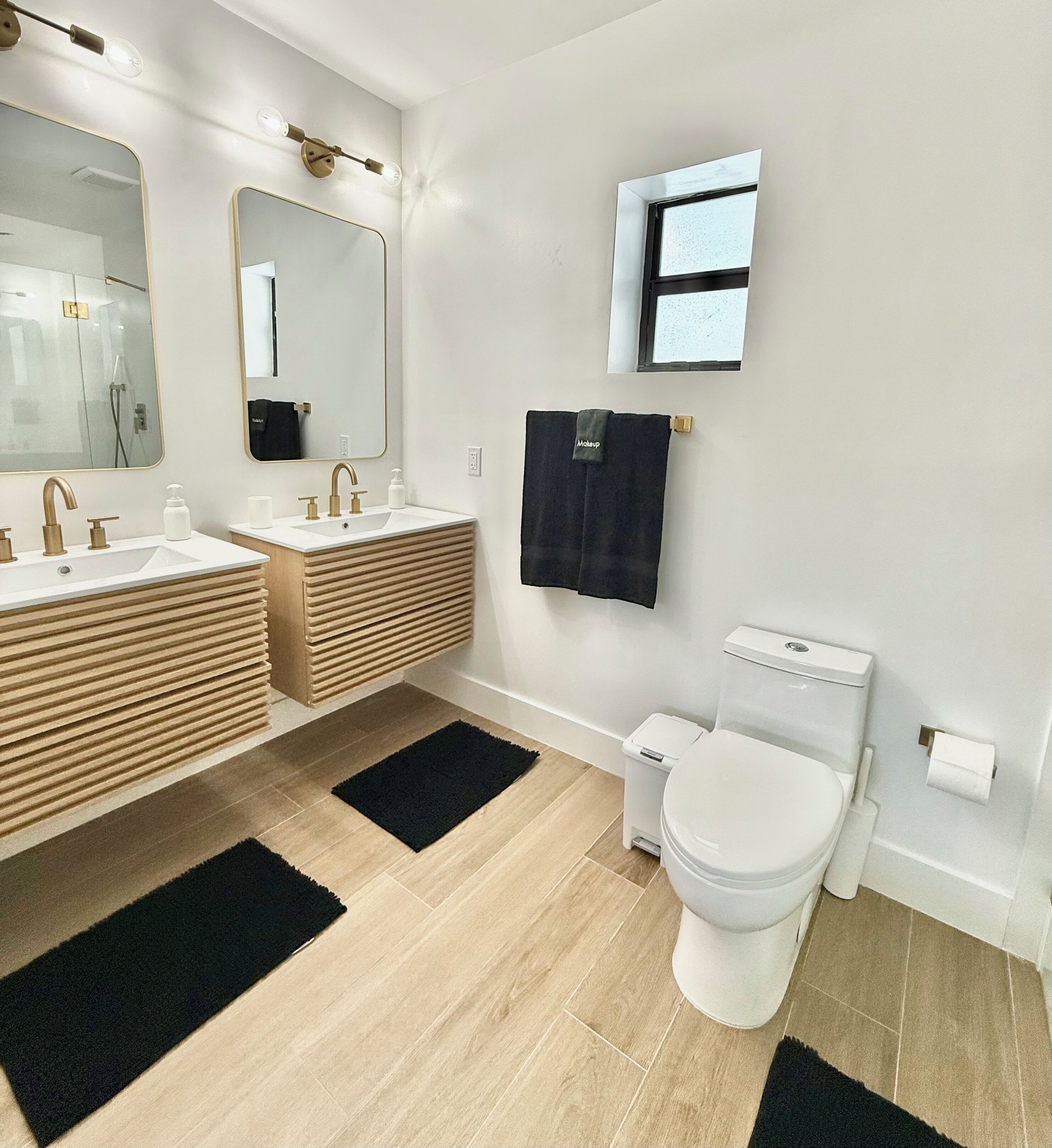 Un baño moderno con dos lavamanos, un inodoro y un espejo.
