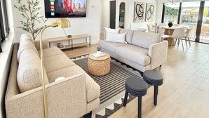 Ein modernes Wohnzimmer mit einer Couch, einem Couchtisch und einem an der Wand montierten Flachbildfernseher.