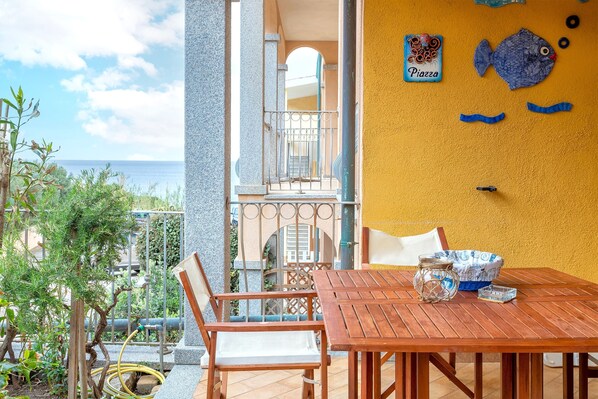 A wooden table with chairs, a yellow wall, and a view of the sea.