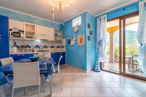 A kitchen with a microwave, stove, and dining area with chairs and a table.