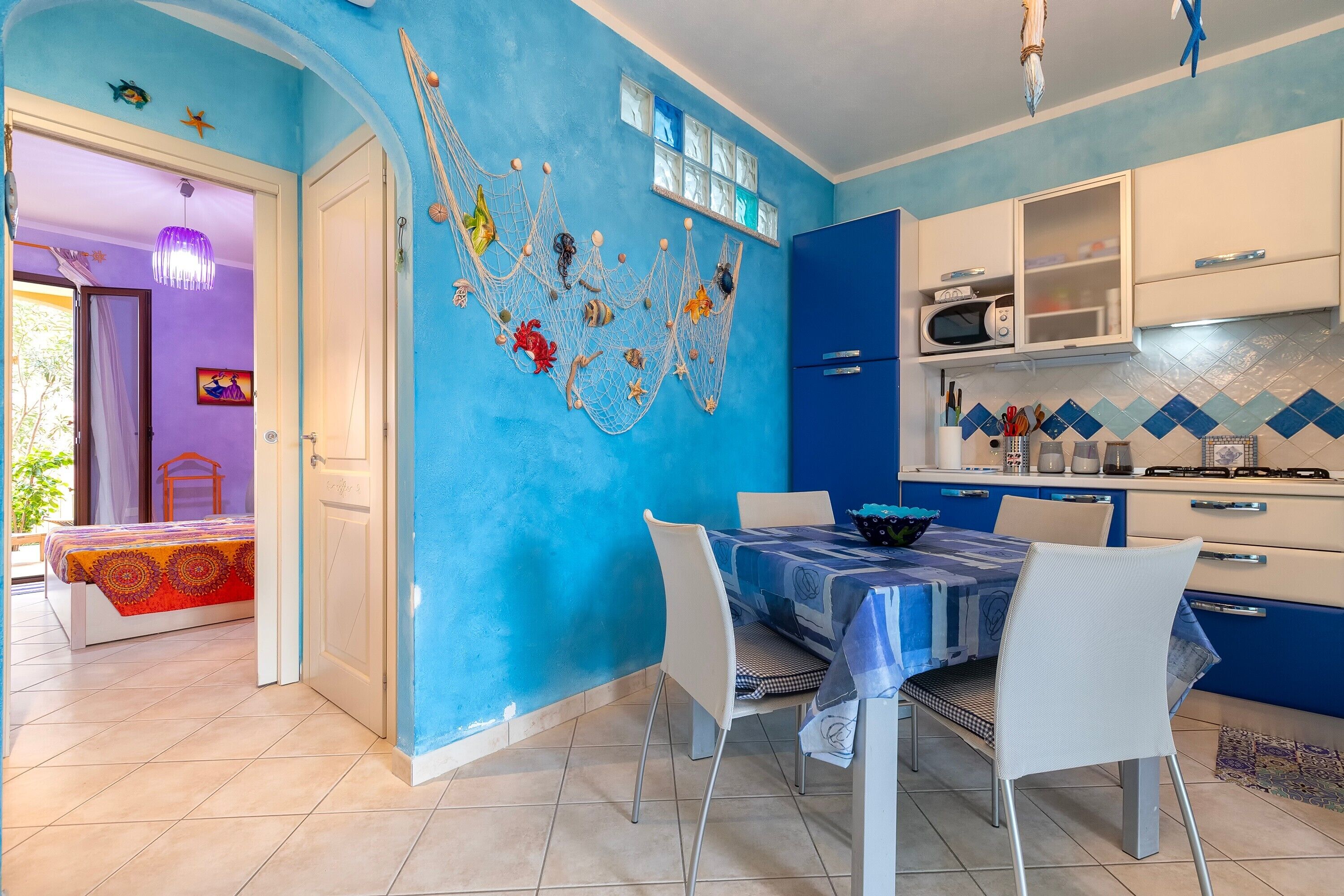 A room with a blue wall, white door, and a dining area with a table and chairs.