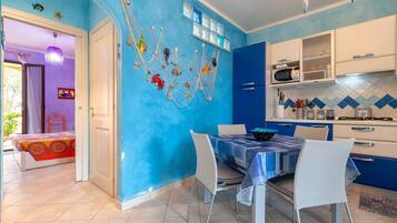 A room with a blue wall, white door, and a dining area with a table and chairs.