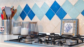 Una cocina con estufa a gas, utensilios y recipientes sobre la encimera.