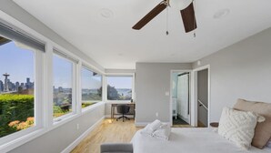 A modern bedroom with a large bed, a desk, and a view of the city skyline. - 3BR 3BA Kerry Park Retreat in Queen Anne, Near Stadium (Seattle)