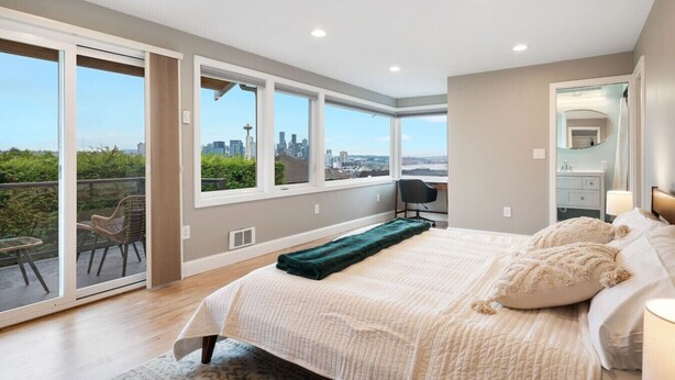 A modern bedroom with a large bed, a desk, and a view of the city skyline through large windows. - 3BR 3BA Kerry Park Retreat in Queen Anne, Near Stadium (Seattle)