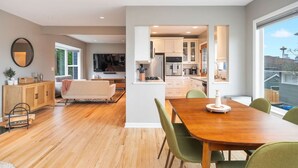 A modern living space with a dining area, kitchen, and a large window offering a view of the city skyline. - 3BR 3BA Kerry Park Retreat in Queen Anne, Near Stadium (Seattle)