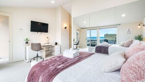 Een moderne hotelkamer met een groot bed, een bureau, een televisie en een balkon met uitzicht.