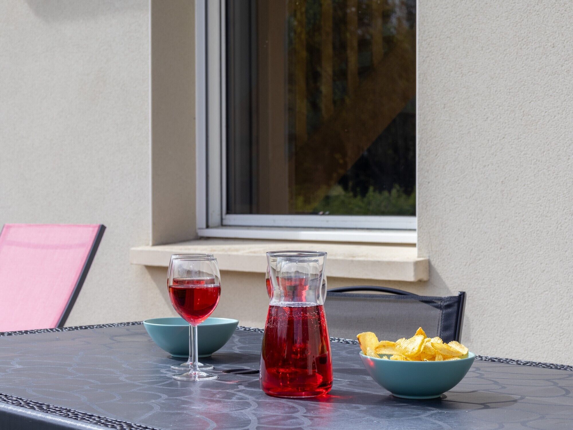 Ein Tisch mit einem Glas rotem Getränk, einer Flasche und einer Schüssel Chips.
