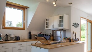 A modern kitchen with white cabinets, a wooden countertop, a built-in island, and a window providing natural light. - 'Maison De Charlie' by Madame est Servie – private terrace, garden, and Wi-Fi (Trégastel)