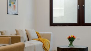 Una sala de estar con un sofá, una mesa redonda de centro y un jarrón de flores.