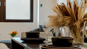 Comedor con encimera oscura, cuencos negros, una copa de vino y plumas de pampa en un florero.