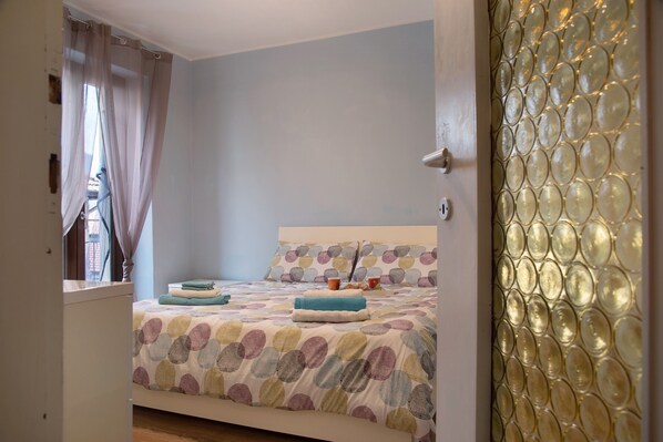 Une chambre à coucher avec un lit, des rideaux, une fenêtre et un mur décoratif en verre.